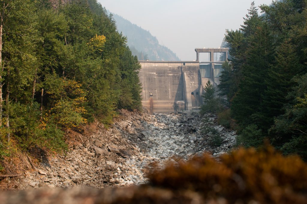 Gorge Dam is framed by forested hills above a dry Skagit riverbed. 