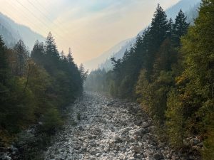 The exposed gravel of the Skagit riverbed between Gorge dam and powerhouse extends beneath power lines and smoky skies and in early October 2022. 